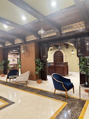 A lobby with a reception desk, two blue armchairs, and potted plants. - Wow Al Zahra Apartments (Jeddah)