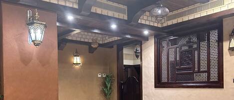 A living room with a sofa, two armchairs, a small table, and decorative wall sconces.