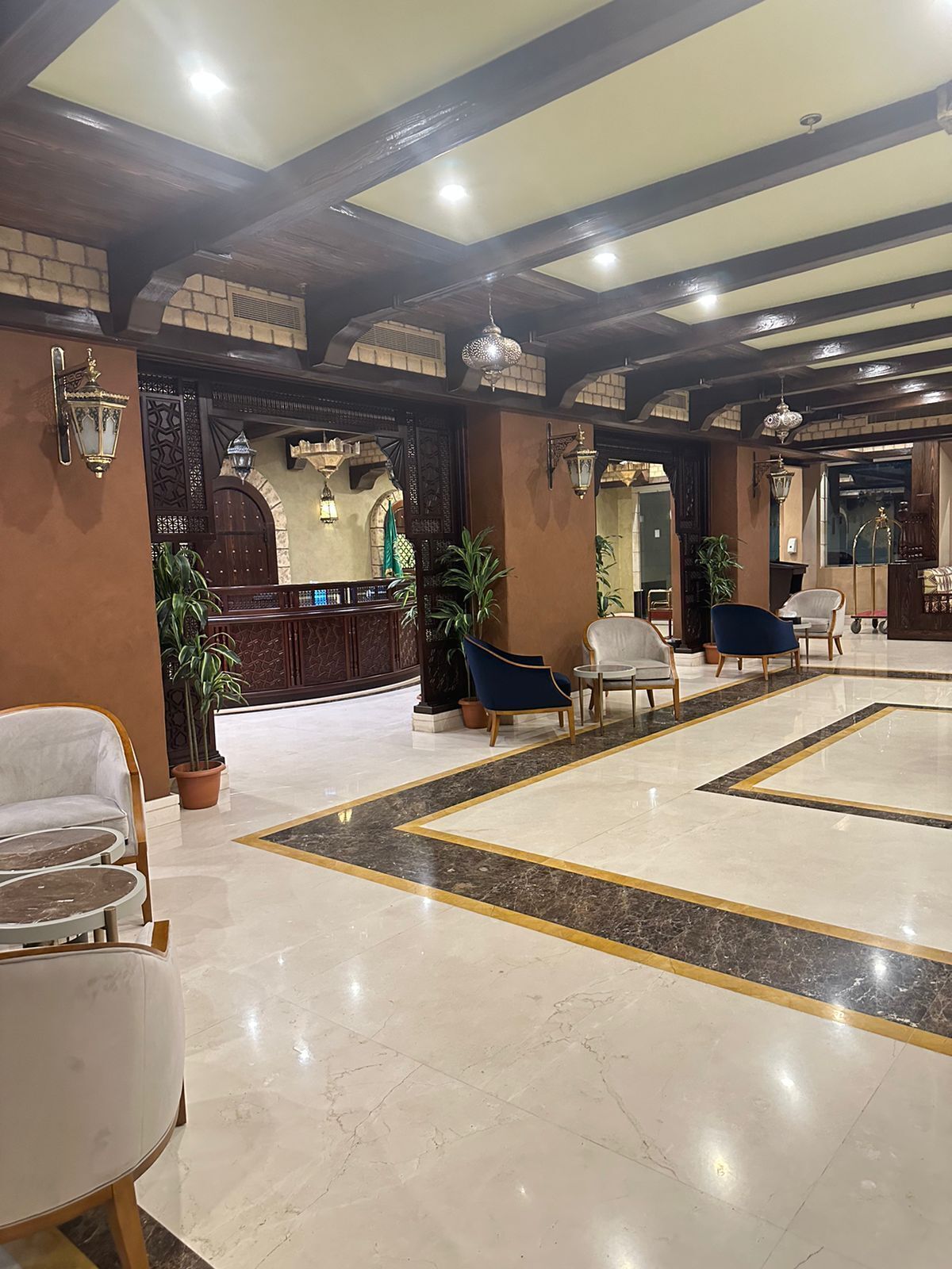 A spacious lobby with a reception desk, seating area, and decorative lighting.