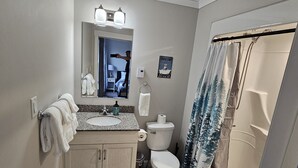 A bathroom with a sink, toilet, and shower curtain.
