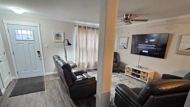 A living room with a sofa, a TV, and a ceiling fan.