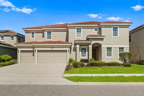 A two-story house with a red-tiled roof, beige exterior, and a garage. - Arcade, Waterpark, Theater, LEGO Room, Pool & Spa, Dual 86” TVs: Paradise Palms (Davenport)