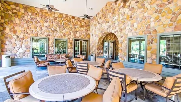 A spacious outdoor area with stone walls, multiple seating arrangements, and ceiling fans. - Entire Condo 3B3B/Resort Style/Close to theme park (Davenport)
