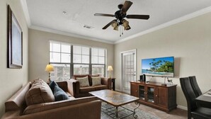 A living room with a sofa, coffee table, TV, and ceiling fan. - Entire Condo 3B3B/Resort Style/Close to theme park (Davenport)