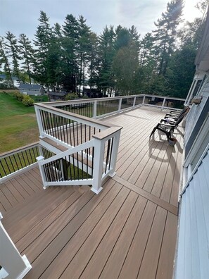 Une terrasse en bois avec des balustrades blanches, une petite table et une chaise.