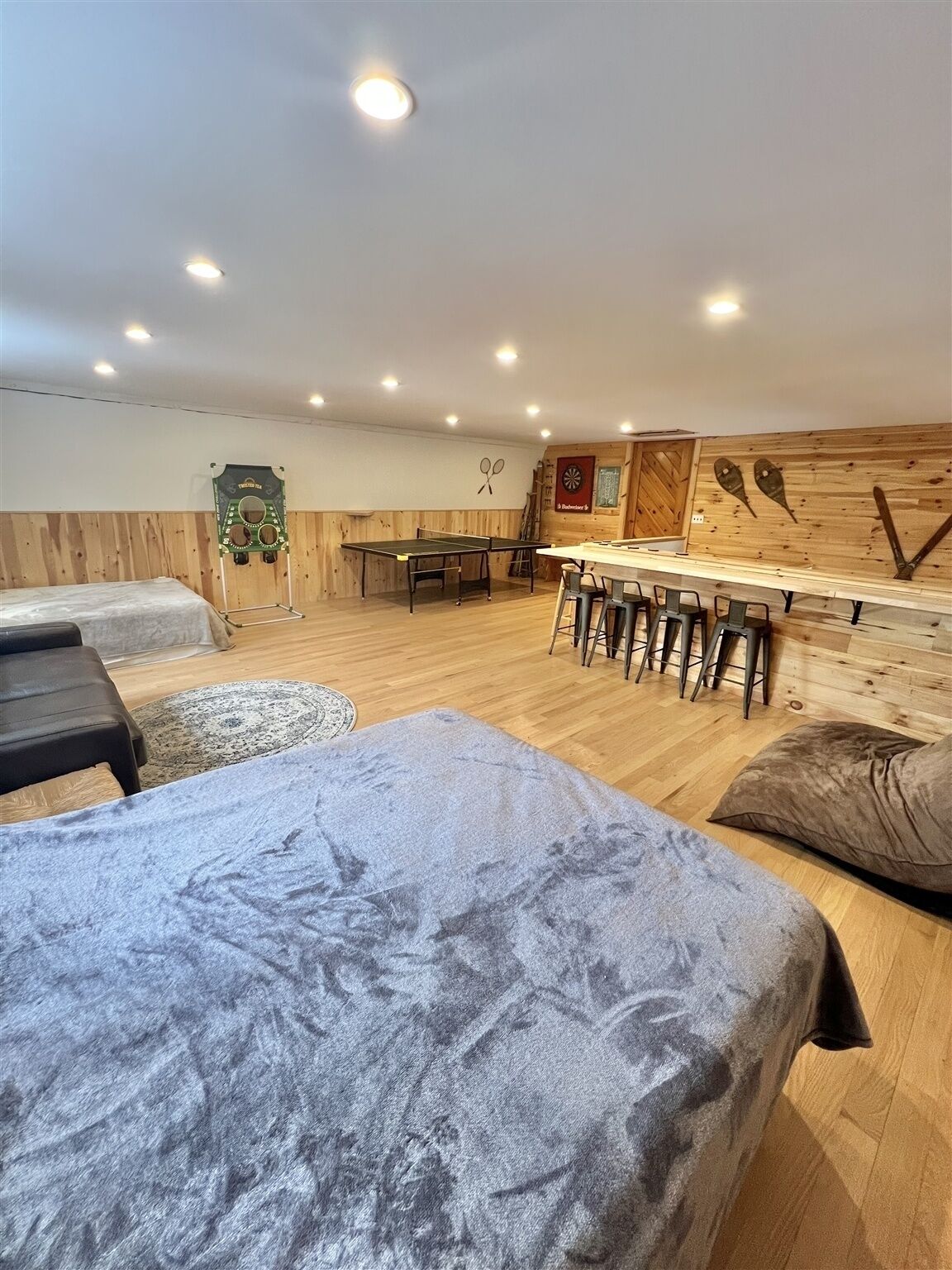 A cozy room with a ping pong table, a dartboard, and a wooden wall with sports memorabilia.