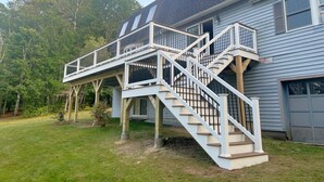 A two-story house with a covered porch and a staircase leading to the upper level. - Loons View Limit 20 5 Bedroom Home (Naples)