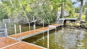 A wooden dock extending into a body of water, surrounded by trees and a small house with a deck. - Loons View Limit 20 5 Bedroom Home (Naples)