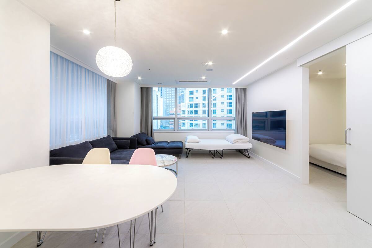 Una sala de estar moderna con un sofá, una mesa de comedor y un televisor montado en la pared.