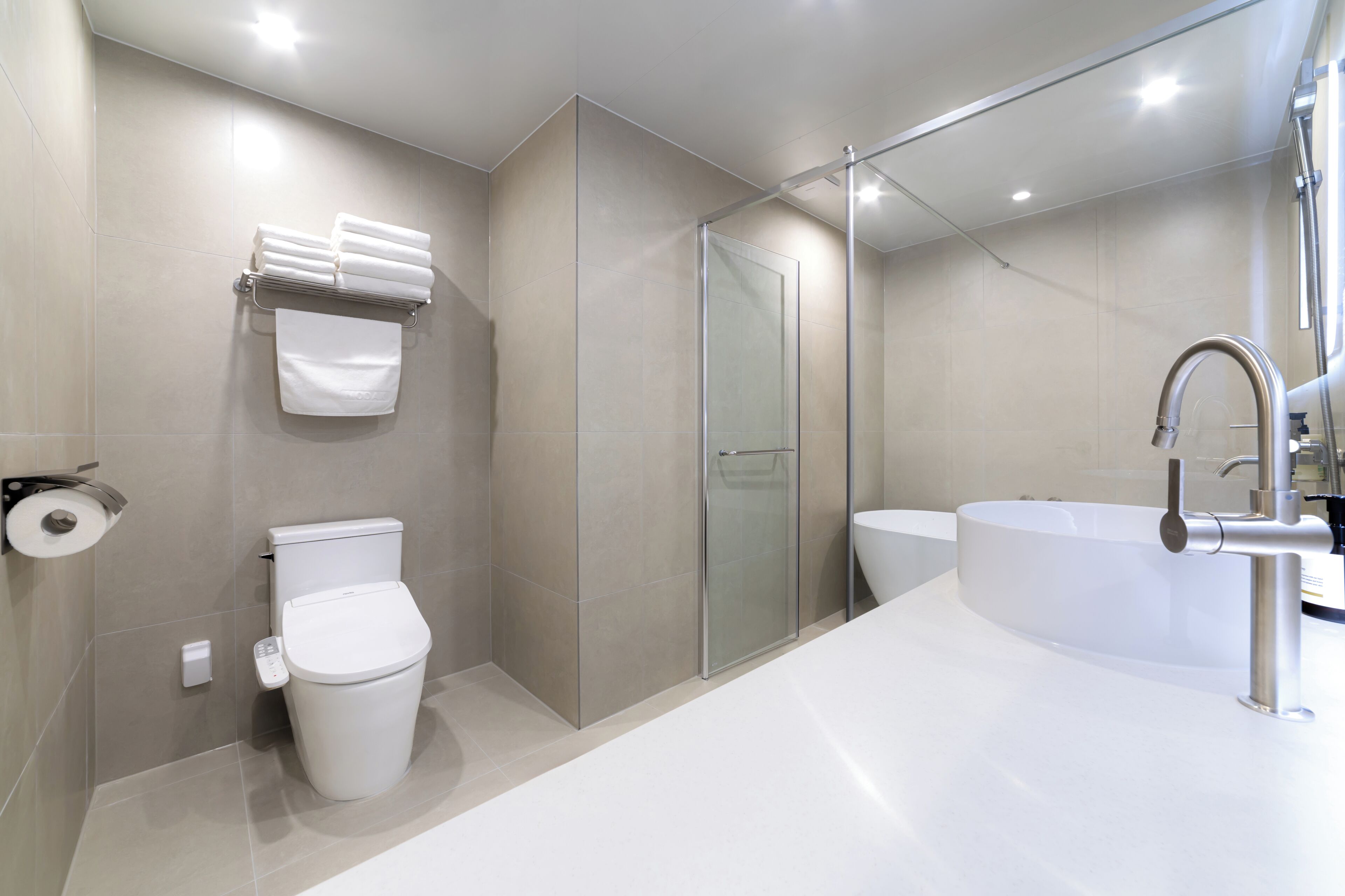 A modern bathroom with a toilet, a glass shower enclosure, and a large bathtub.