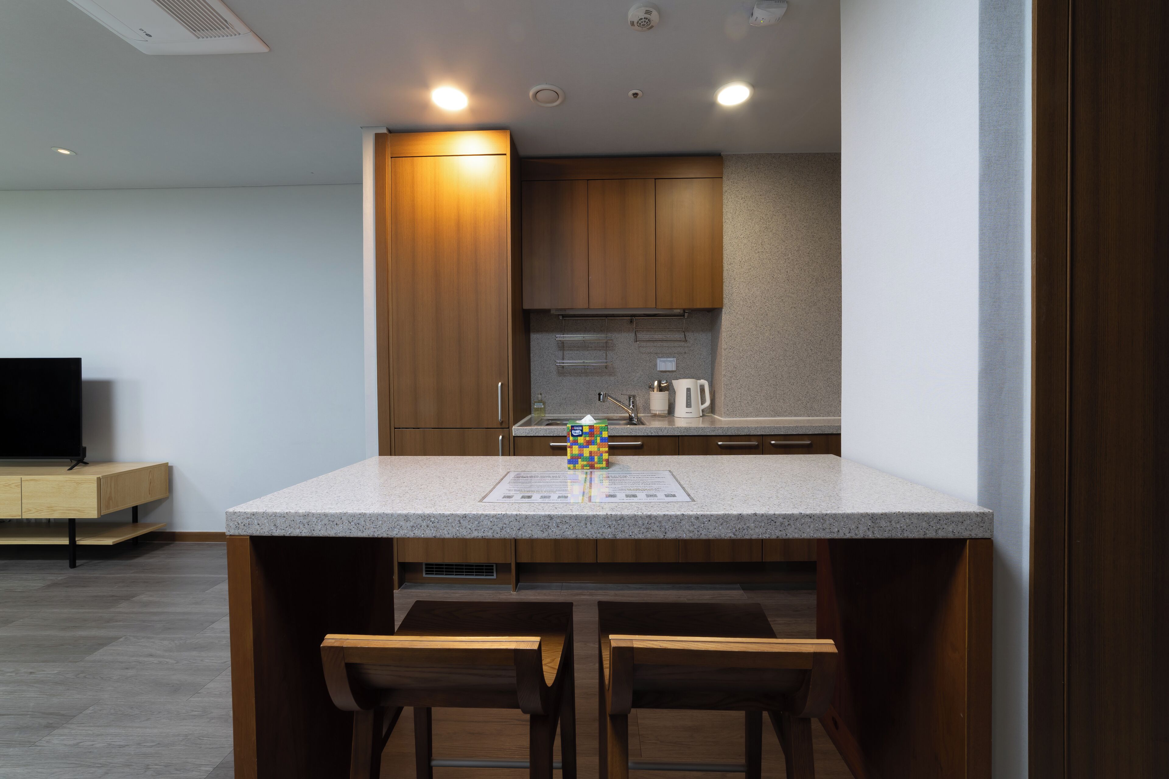 Una cocina moderna con armarios de madera, encimera de granito y una zona de bar con dos taburetes.