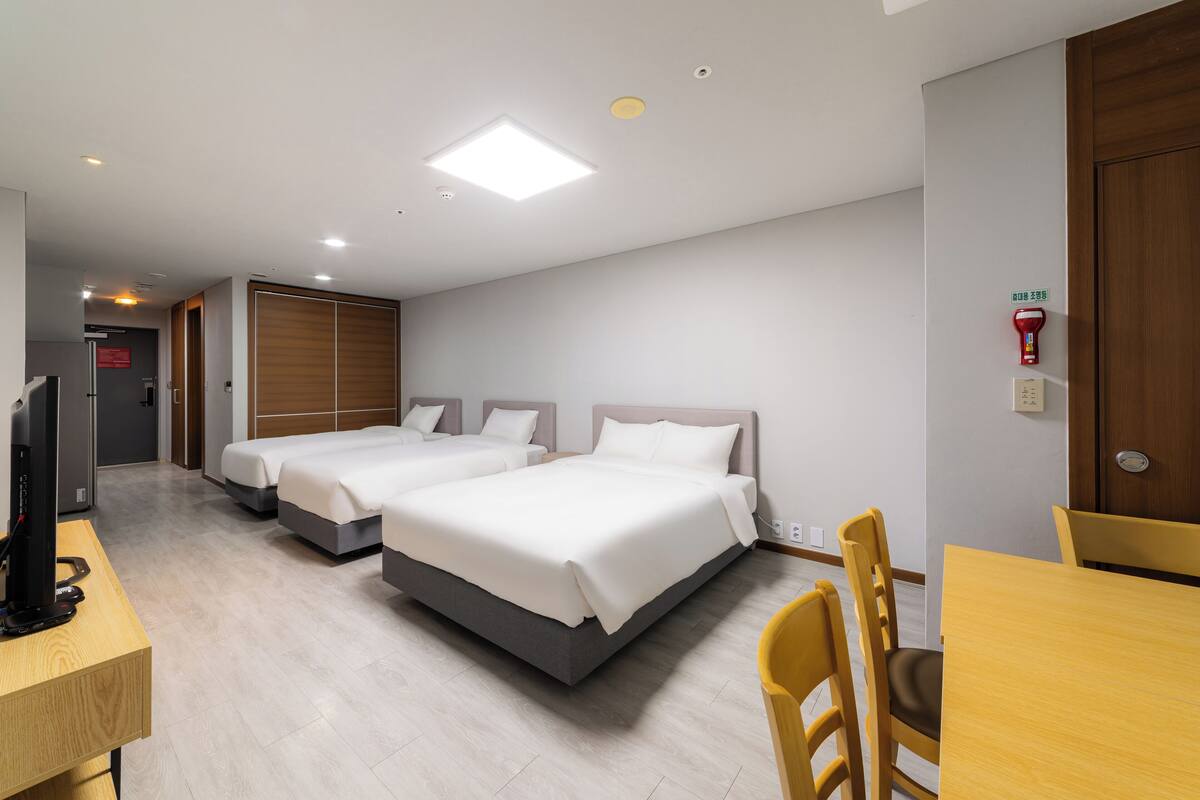 Habitación de hotel con dos camas, un escritorio, una silla y un televisor.