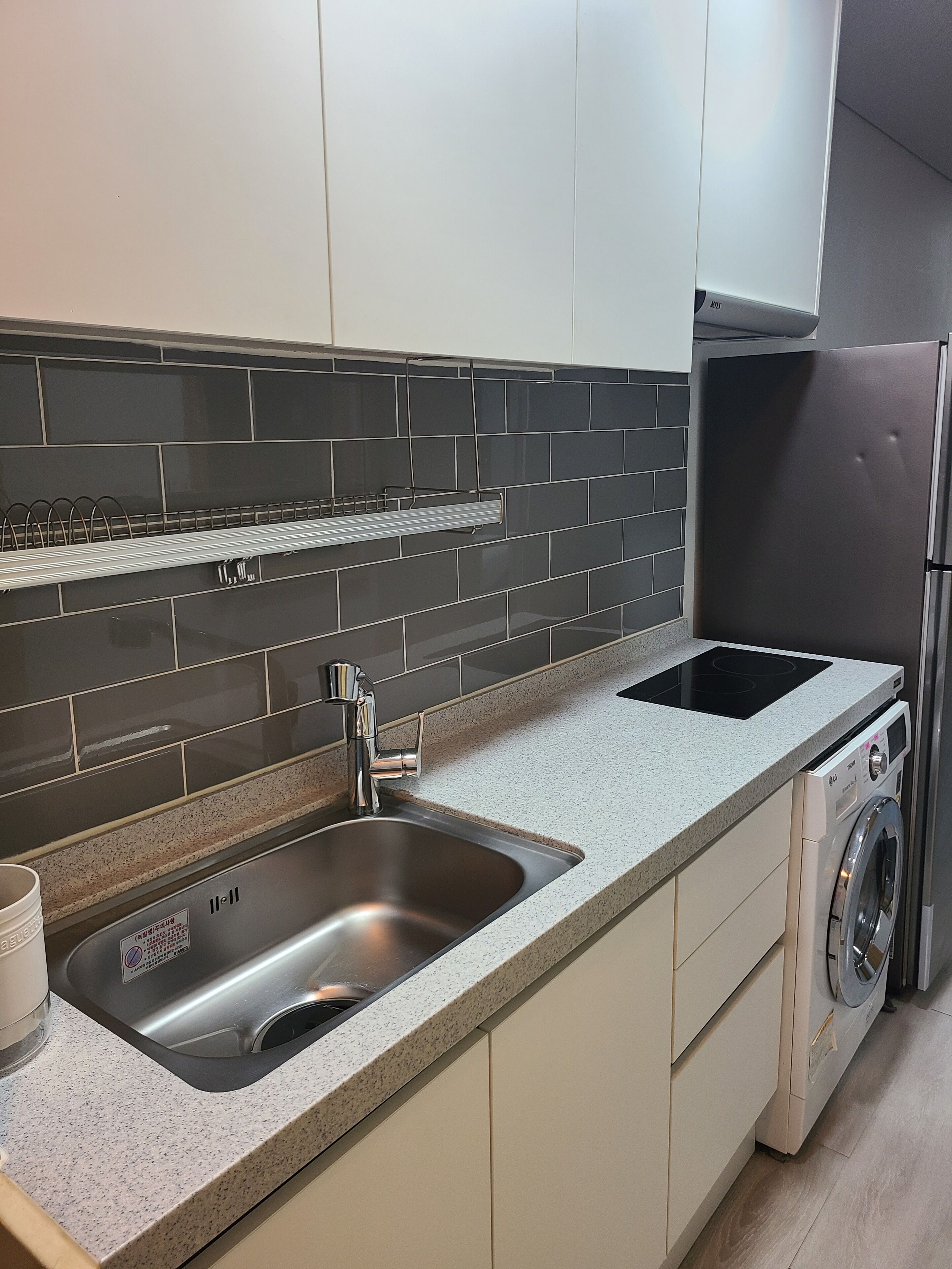 A modern kitchen with a stainless steel sink, a built-in oven, and a washing machine.