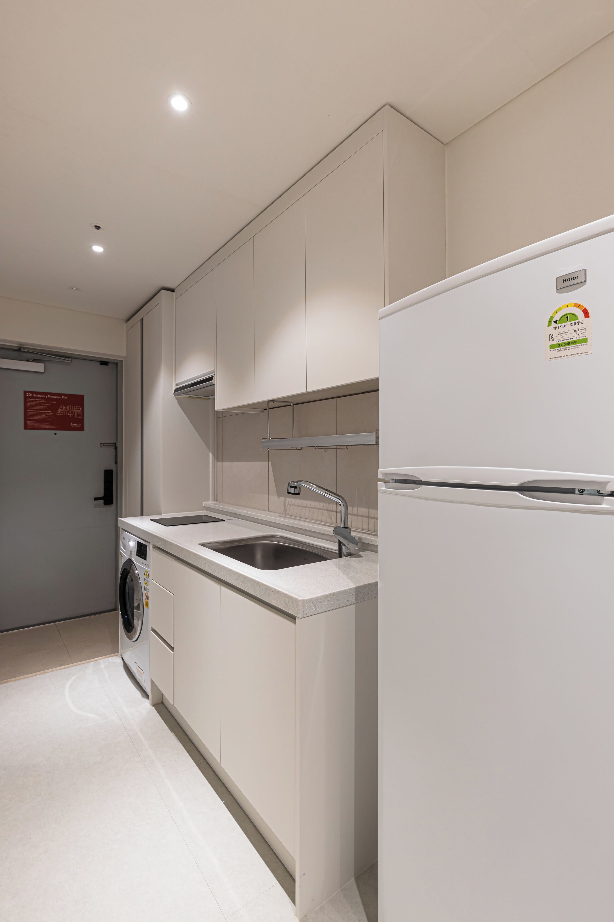 A modern kitchen with a built-in washing machine, a sink, and a refrigerator.