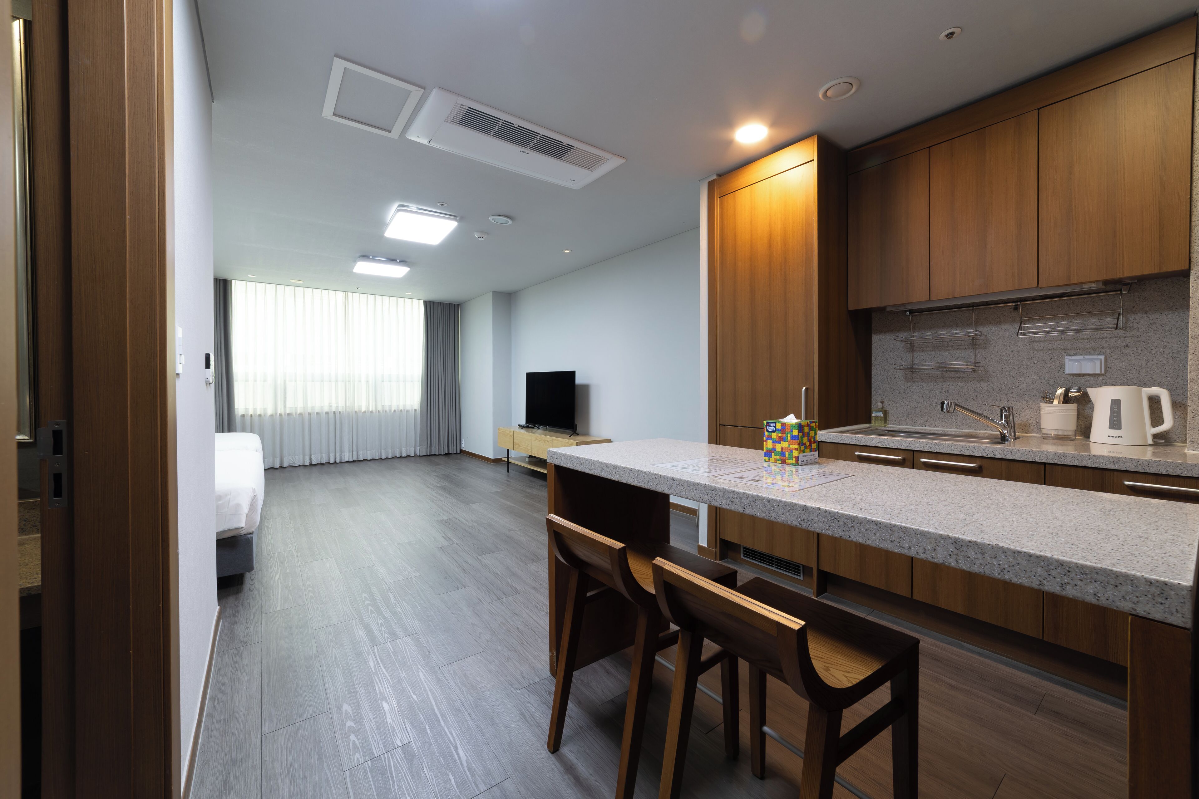 A modern kitchen with wooden cabinets, a granite countertop, and a built-in stove. There is a dining area with two wooden chairs and a small table.