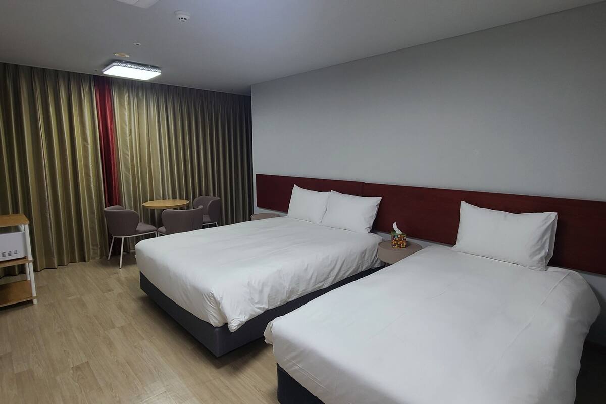 Habitación de hotel con dos camas, un escritorio y una silla.