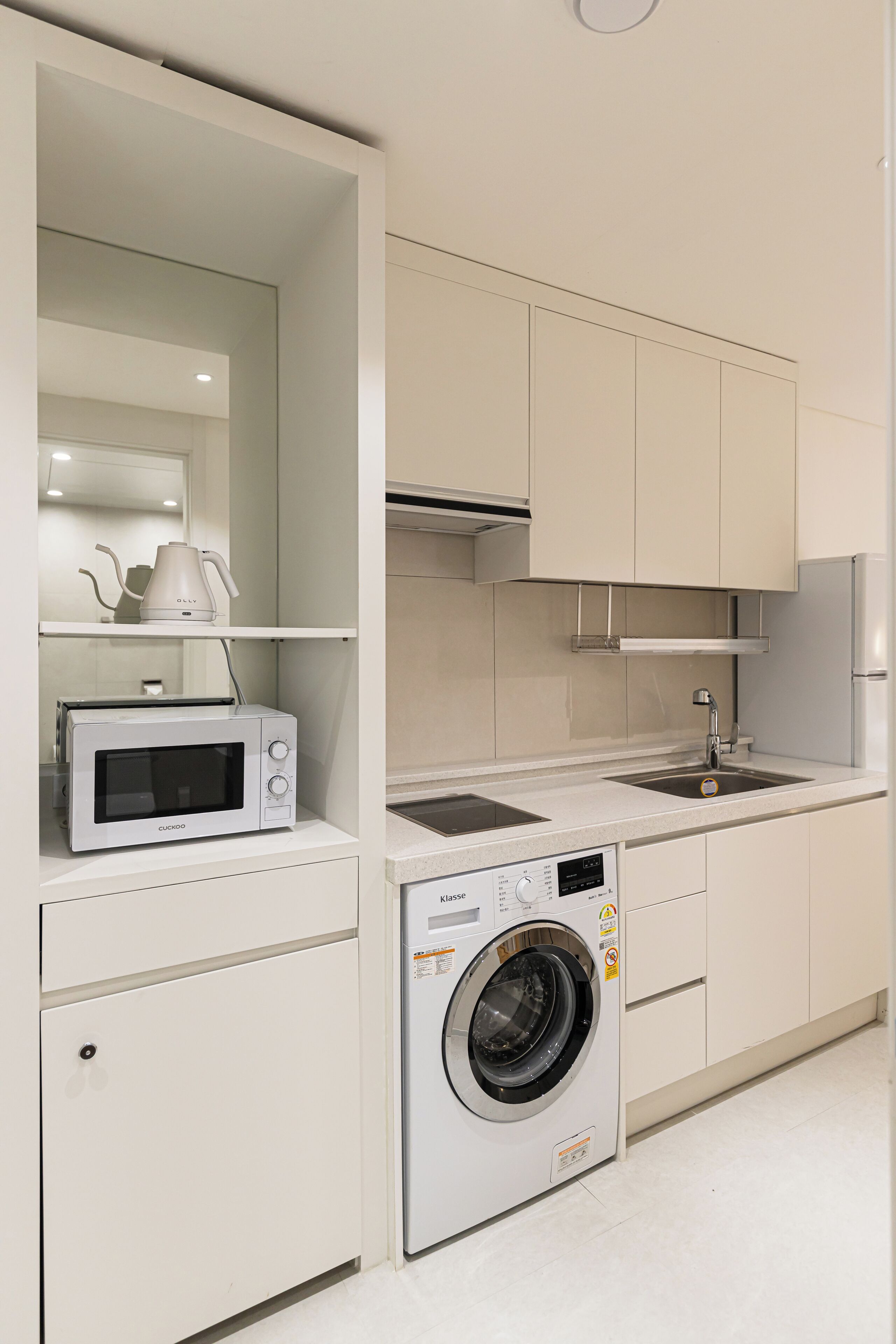 Una cocina compacta con microondas integrado, lavadora y lavaplatos.