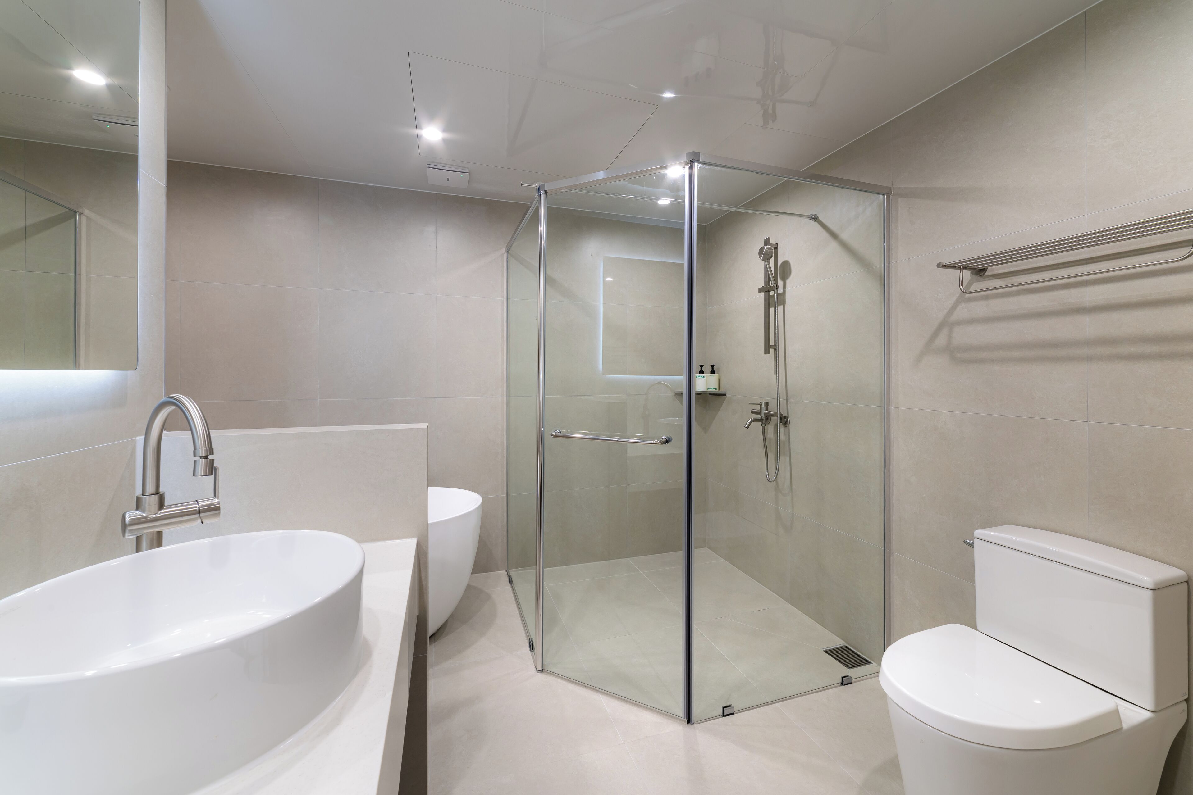 Un baño moderno con ducha de vidrio, lavamanos blanco y retrete.