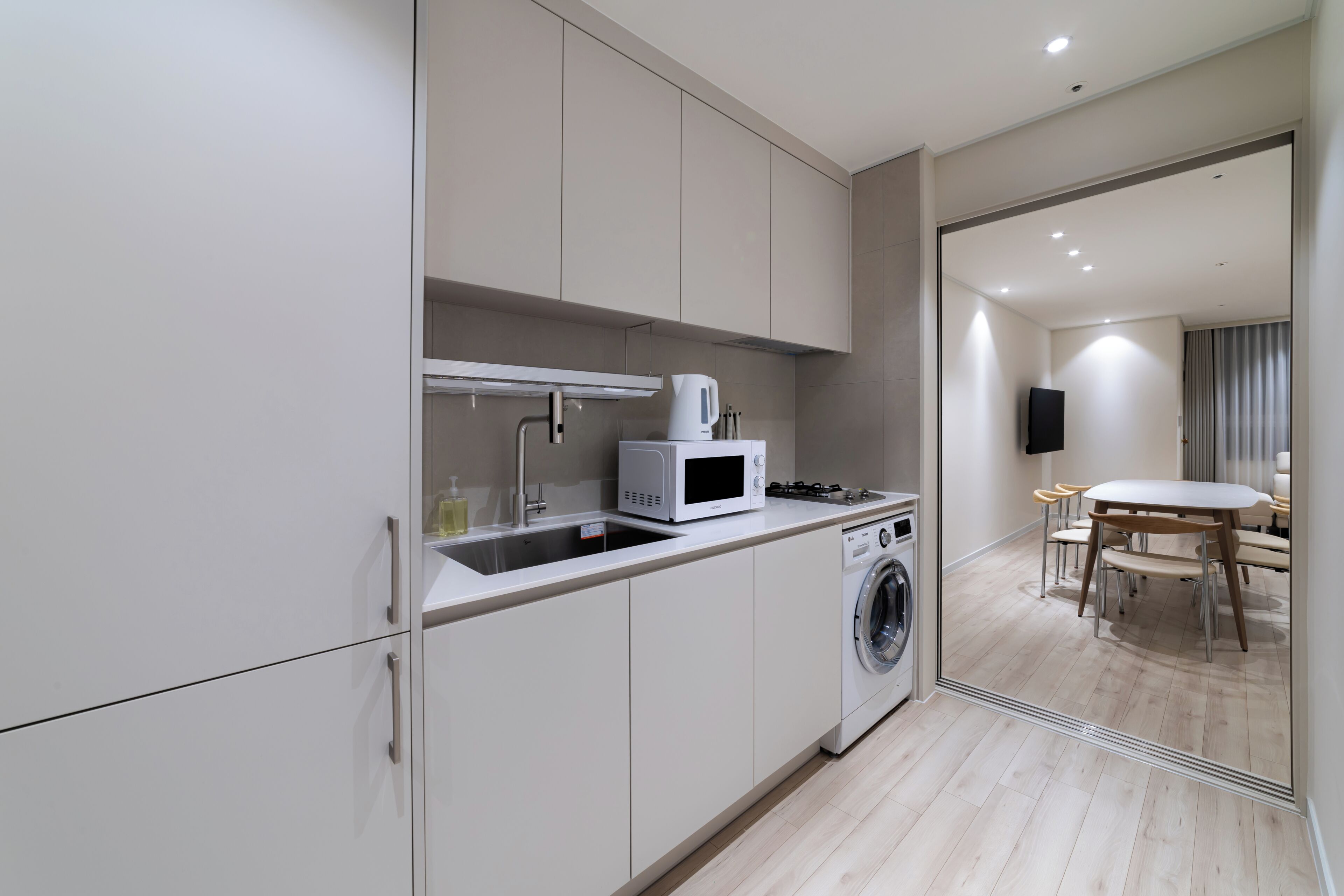 Une cuisine moderne équipée d’un four à micro-ondes, d’un évier et d’un lave-linge.