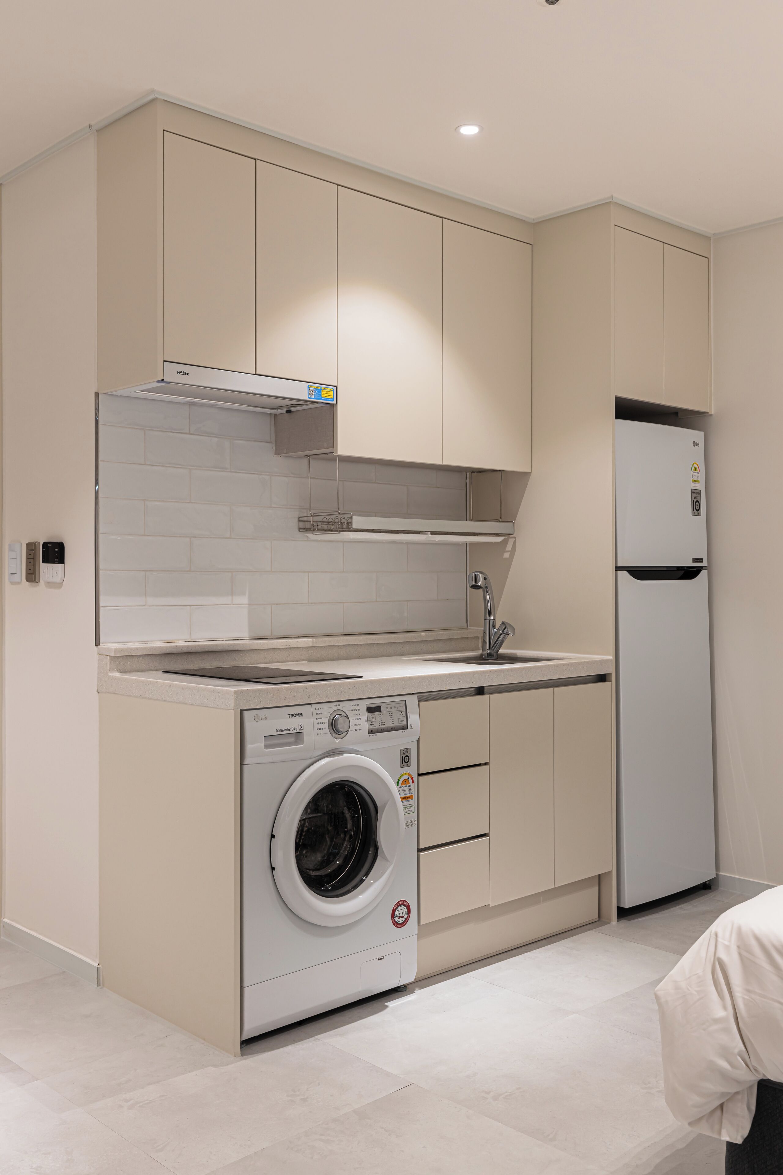 A compact kitchen with a built-in washer and dryer, a refrigerator, and a tiled backsplash.