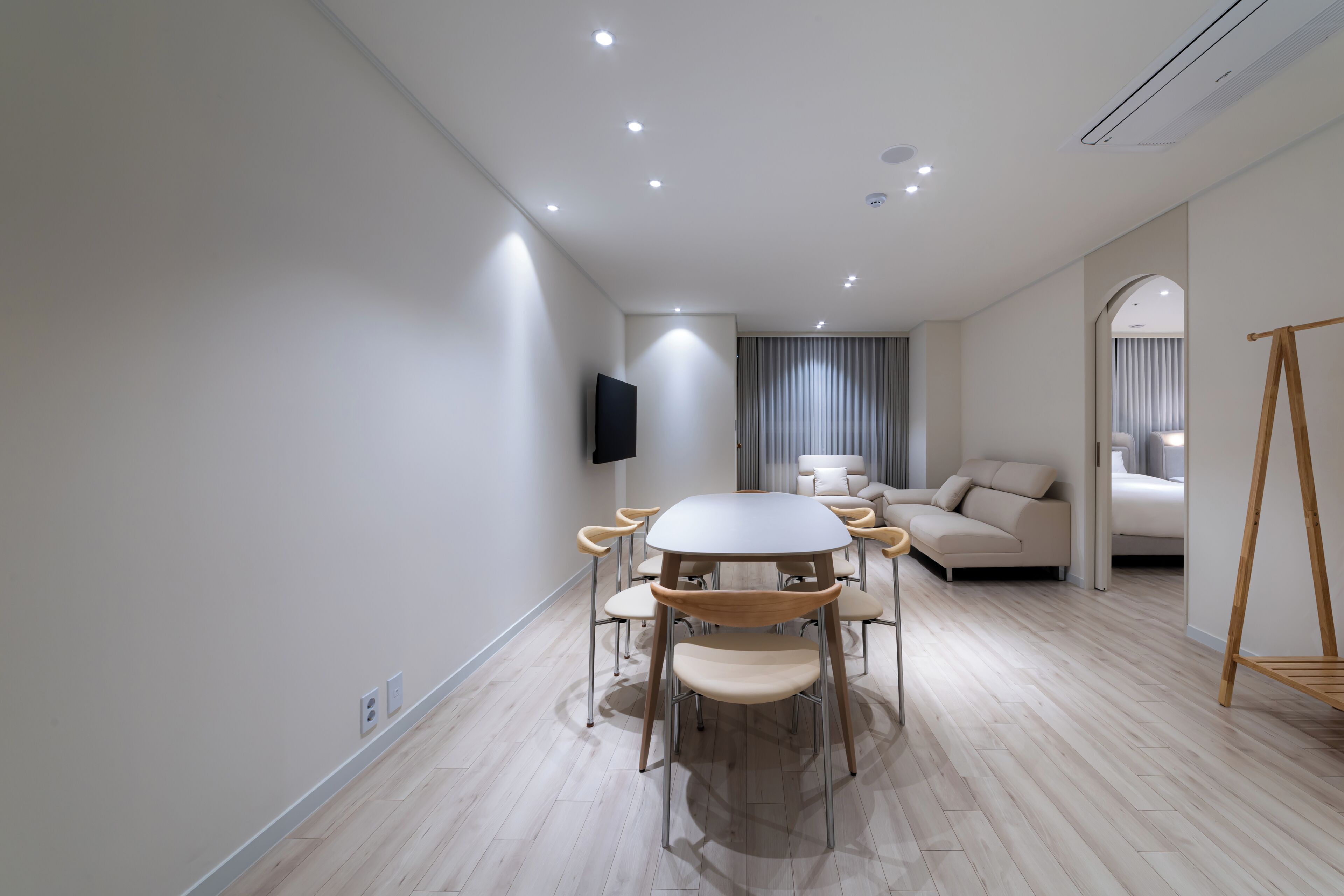 Una sala de estar moderna con una mesa de comedor redonda, un sofá y un televisor montado en la pared.