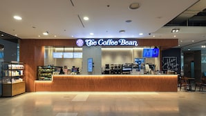 A coffee shop interior with a wooden counter, digital menu boards, and seating area.