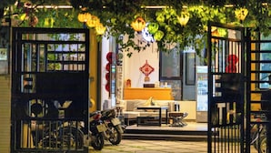 An outdoor seating area with a sofa, coffee table, and motorcycle parked nearby.