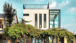 A modern building with a glass facade, a covered entrance with greenery, and a visible number "66".