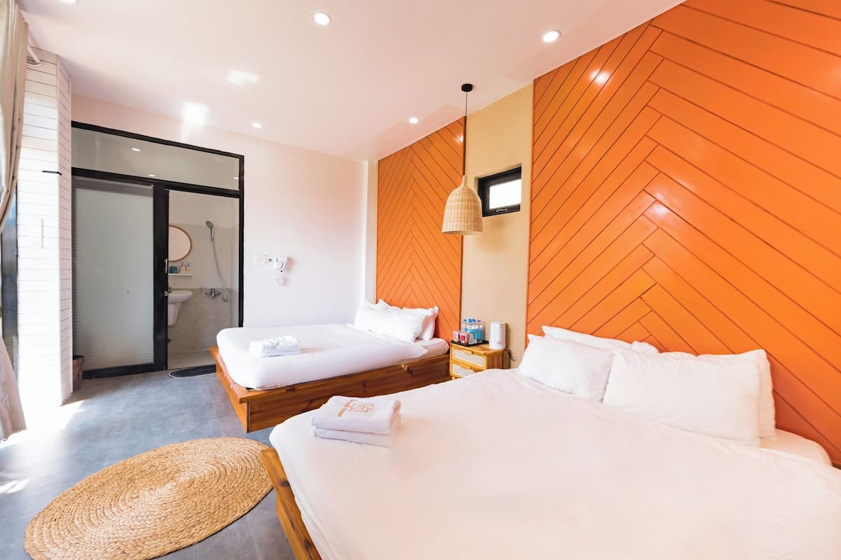 A hotel room with two beds, a shower area, and a wooden accent wall.
