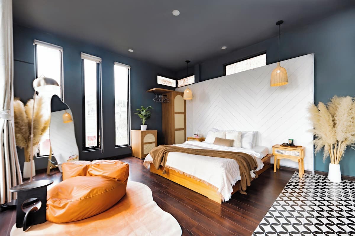 A modern bedroom with a large bed, a wooden nightstand, a small table, and a decorative wall panel.