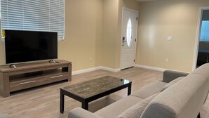 A living room with a flat-screen TV, a wooden entertainment unit, a grey sofa, and a coffee table. - 1280A - 2-bedroom/2 bathrooms in Pasadena (Pasadena)