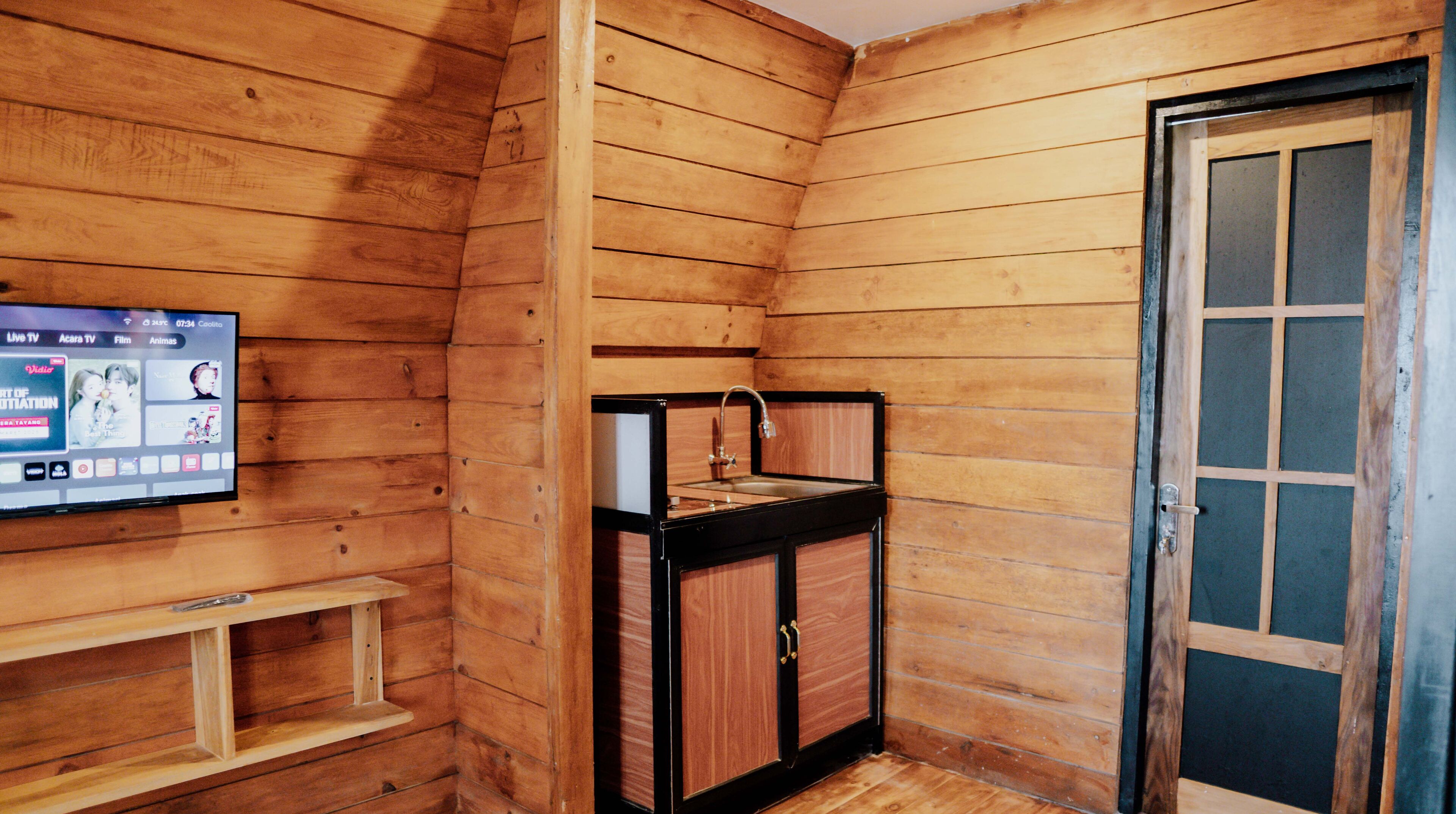 A wooden cabin with a wooden wall, a small sink, and a door with glass panels.