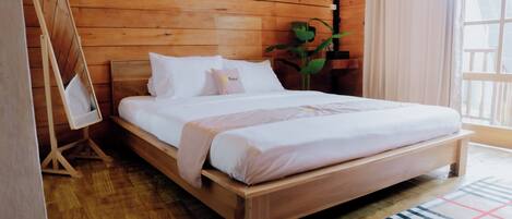 A wooden bedroom with a bed, a small table, and a plant.