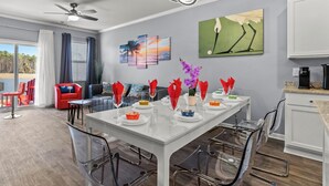A modern dining area with a white table, clear chairs, and a ceiling fan. - Central location Modern Lakefront 2 king-Suite 3 Bedroom 3 Full Bathroom (Myrtle Beach)