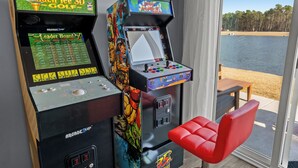 Two arcade machines, a red chair, and a view of a lake. - Central location Modern Lakefront 2 king-Suite 3 Bedroom 3 Full Bathroom (Myrtle Beach)