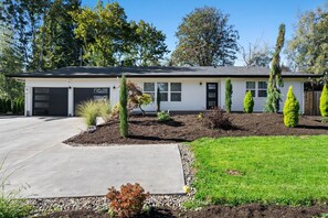 Enjoy a serene stay in this single-story house with a yard featuring lush plants and trees.