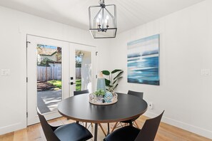 Enjoy meals in this dining area with a round table and four chairs, illuminated by a chandelier.