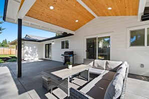 Relax and dine in style in this covered patio area with seating and a grill.