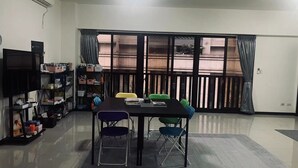 Una habitación con una mesa de comedor, sillas, un televisor y una estantería.
