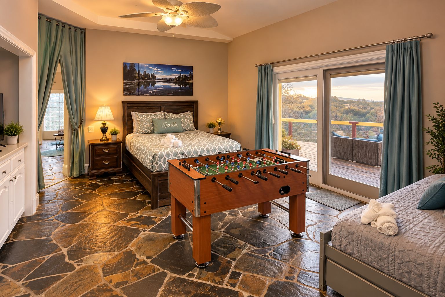 A bedroom with a foosball table, a bed with a view, and a large window.