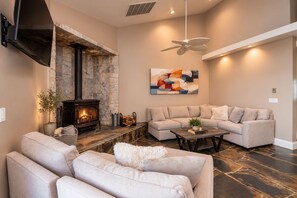A living room with a stone fireplace, a sofa set, a coffee table, and a ceiling fan.