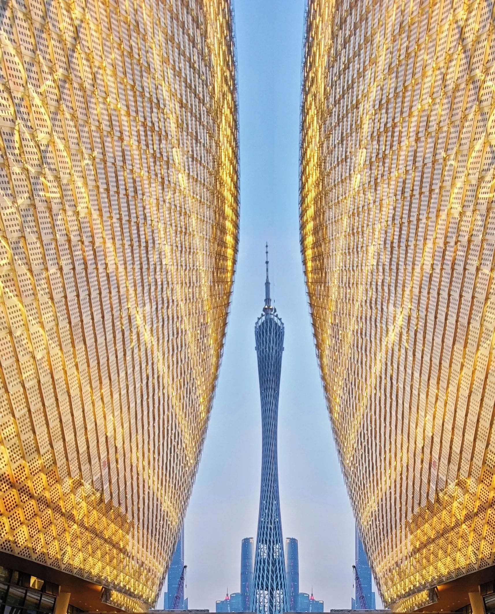 Un edificio moderno con una fachada singular que presenta un diseño de luces en forma de cuadrícula, que guía la mirada hacia una imponente estructura de torre al fondo.