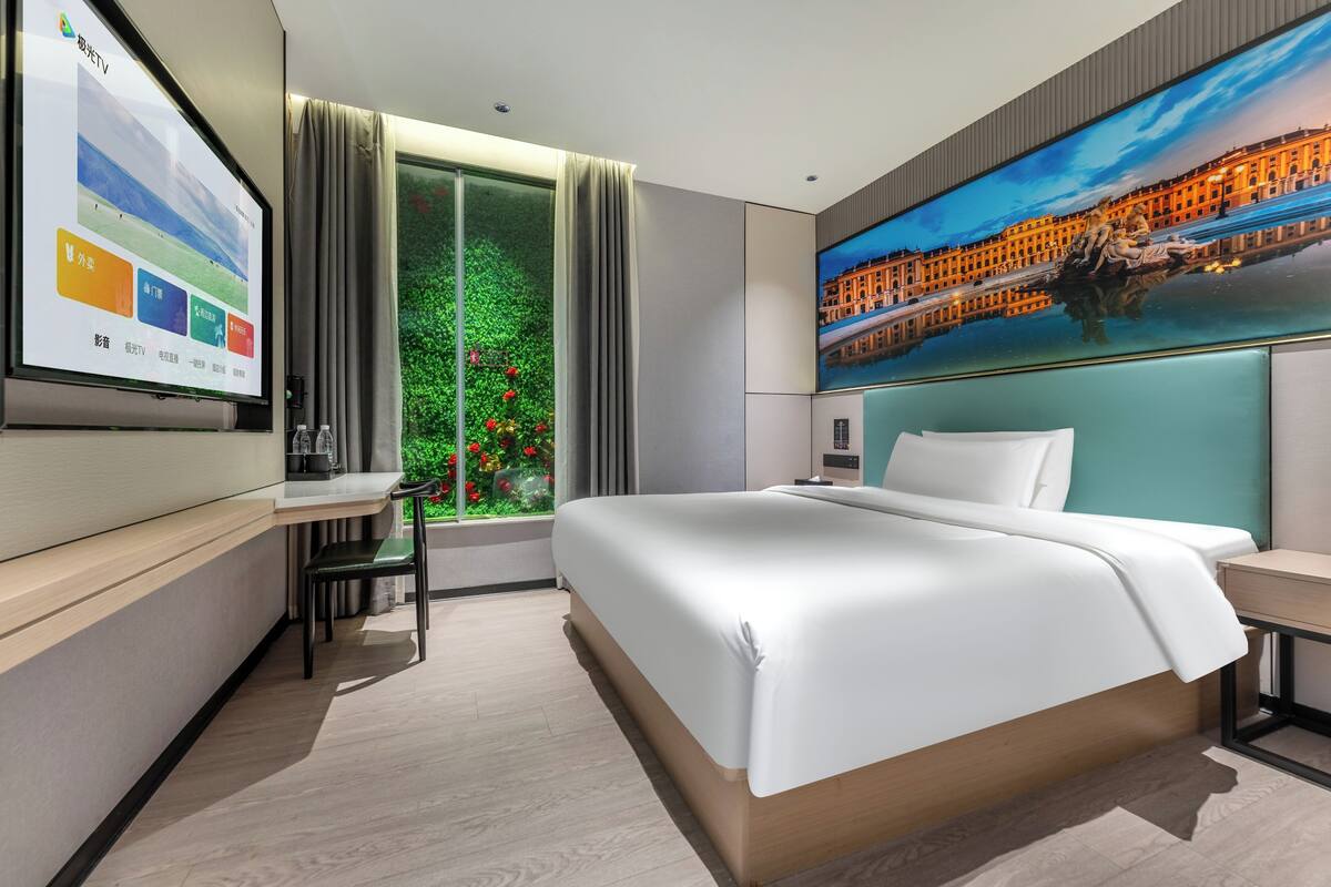Una habitación de hotel moderna con una cama grande, un escritorio y una pantalla de televisión mostrando un menú.