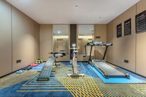 Un gimnasio con cintas de correr, una bicicleta estática y pesas sueltas.