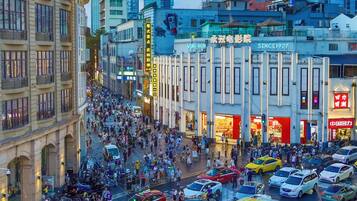 Una calle urbana concurrida, con peatones, vehículos y edificios comerciales.