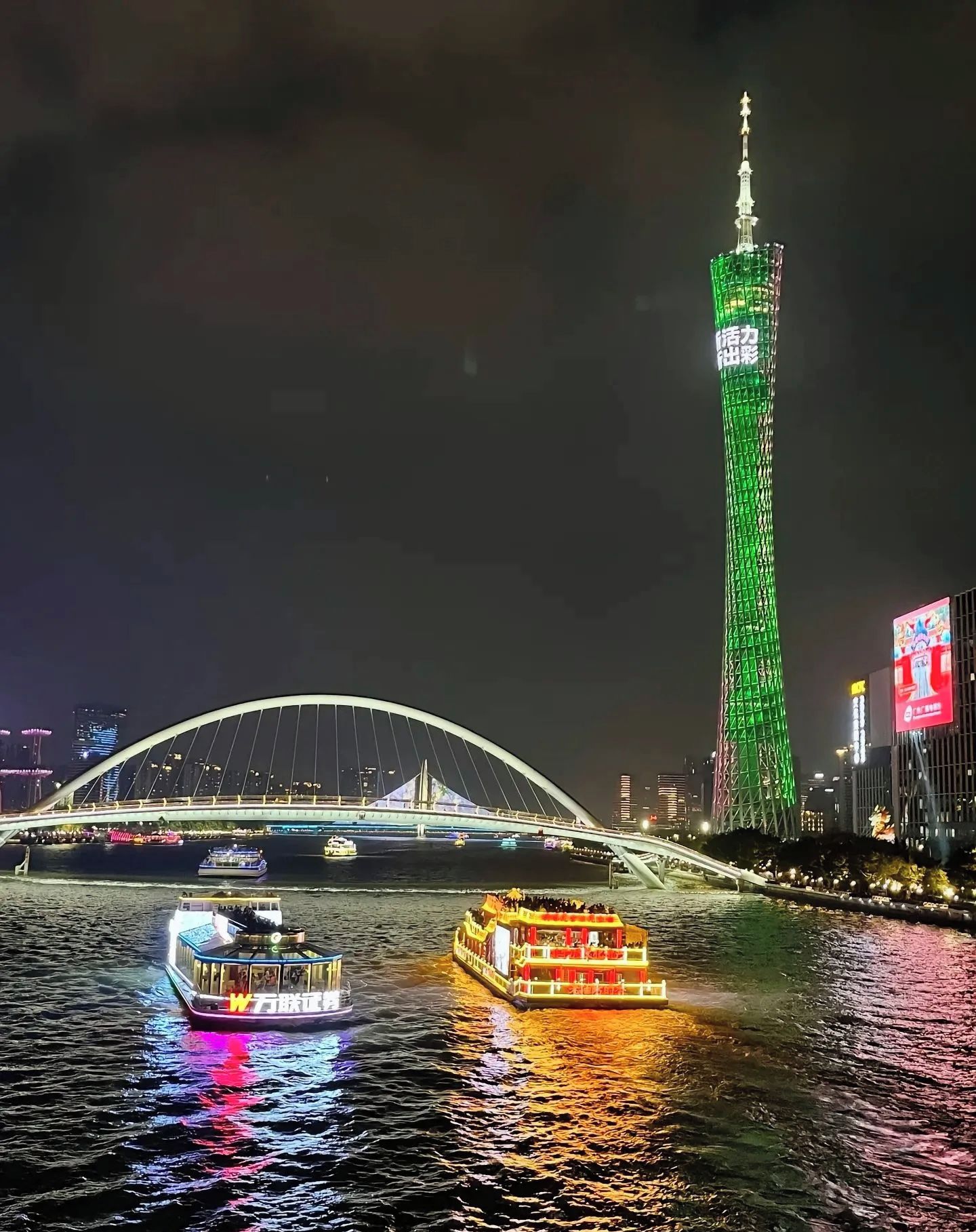 A nighttime river scene with a bridge and a tower.