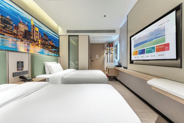 Habitación de hotel con una cama grande, un escritorio, una pantalla de televisión y un cuadro de un paisaje urbano.
