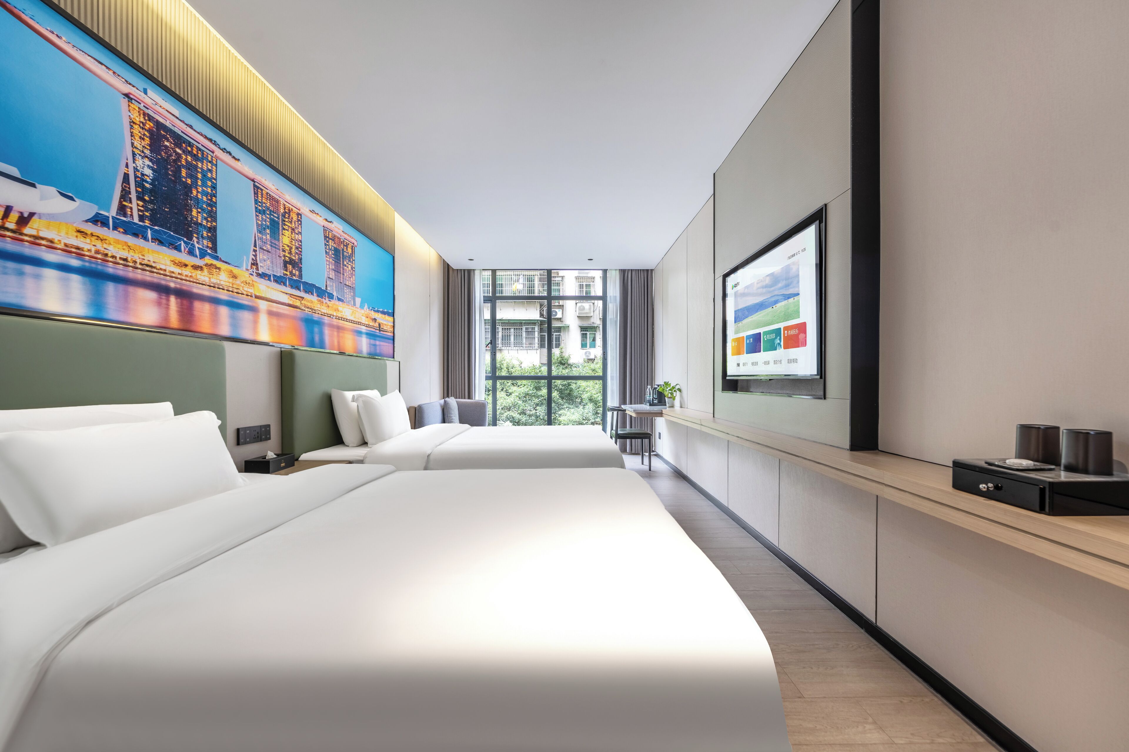 A modern hotel room with a large bed, a desk, and a view of a cityscape through the window.