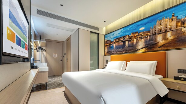 A modern hotel room with a large bed, a nightstand, a desk, and a wall-mounted TV. - Norman Hotel - Binjiang East Road Subway Station, Haizhu District, Guangzhou - Free shuttle service during the Canton Fair (Guangzhou)