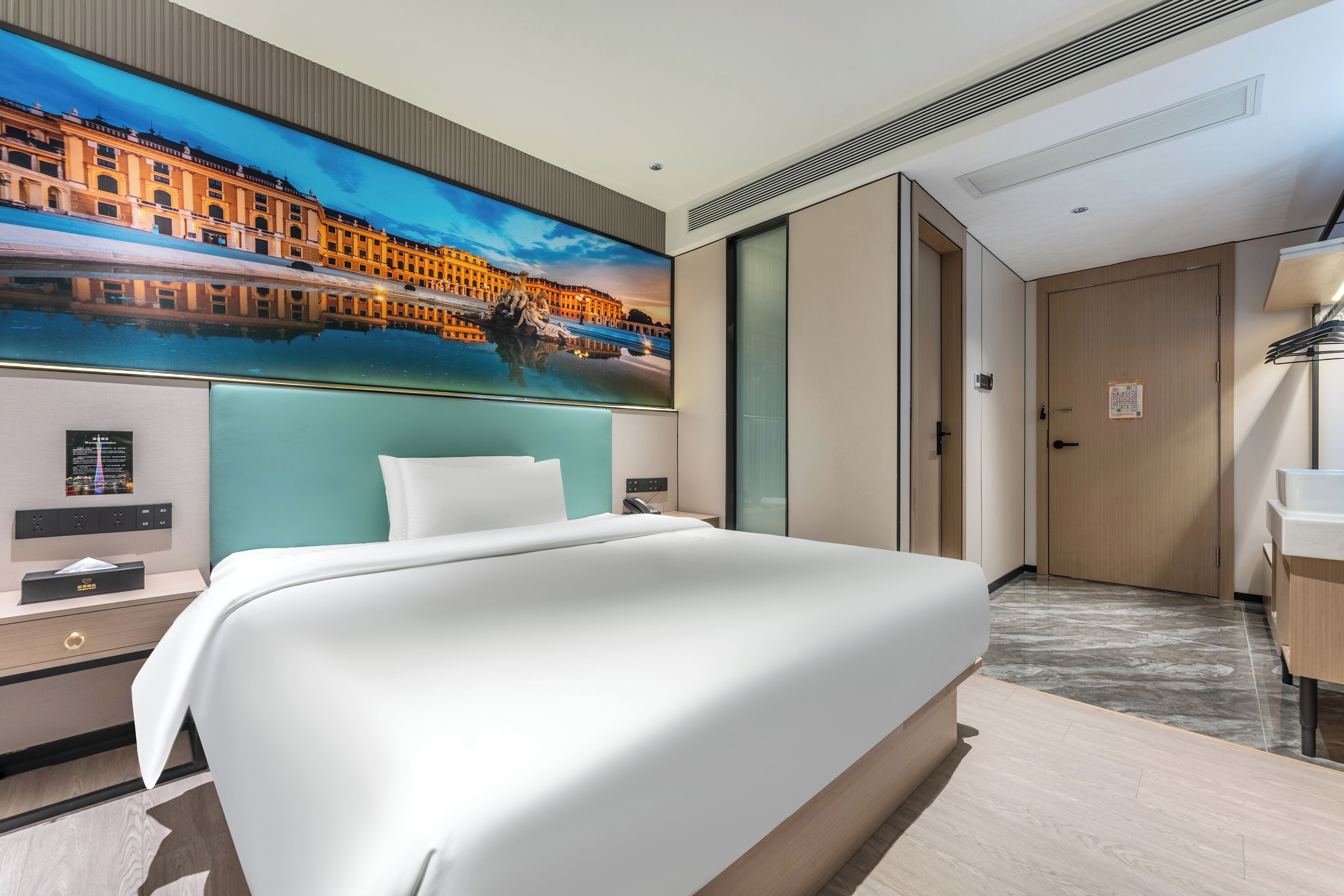 A modern hotel room with a large bed, a nightstand, a desk, and a bathroom.